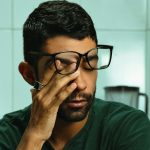 Adult man with glasses sitting at home looking overwhelmed and fatigued, representing ADHD symptoms before an online assessment in Ontario.